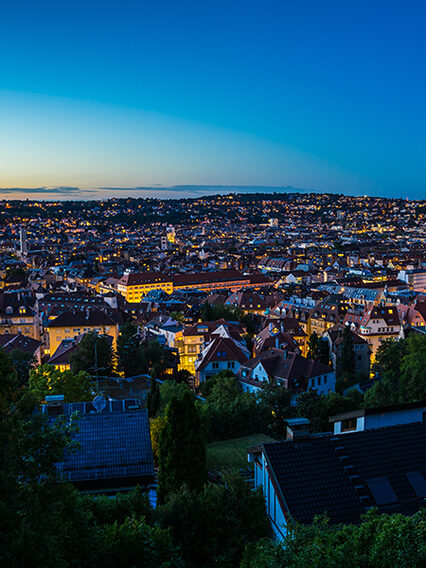 Der Stuttgarter Talkessel in der Abenddämmerung mit vielen beleuchteten Häusern und Straßen.